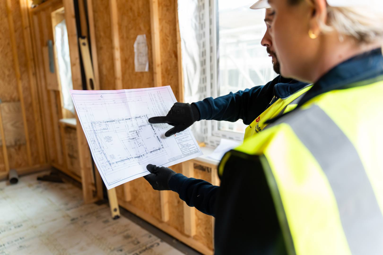 Two workers discussing a cad drawing of a house
